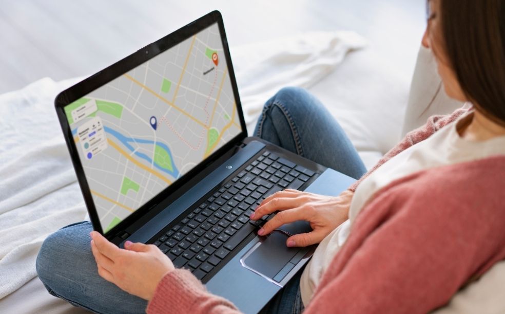 Mulher sentada no sofá pesquisando no notebook um mapa com a localização de uma empresa, ilustrando o que é SEO Local
